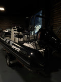 A black and white Brig inflatable boat with a hardtop canopy, shown parked in a dark indoor setting.