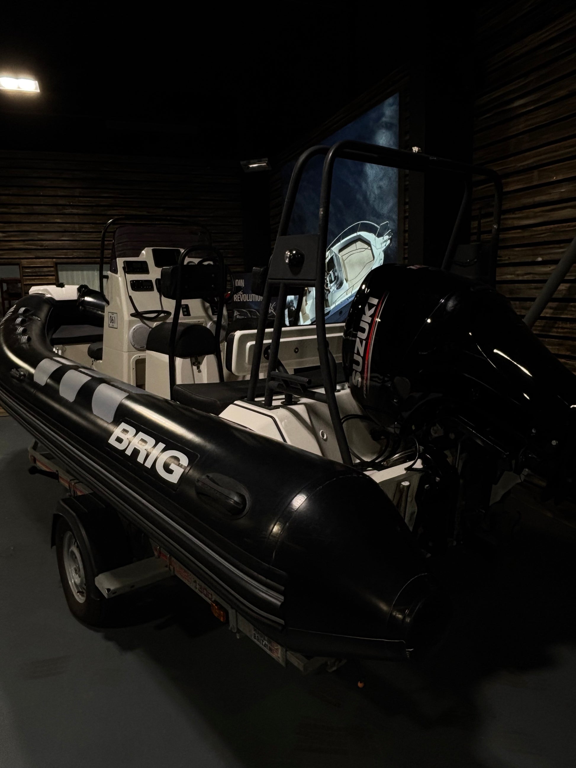 A black and white Brig inflatable boat with a hardtop canopy, shown parked in a dark indoor setting.