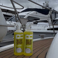 Two bottles of Relay Spray on a boat deck with a cloudy sky.