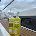 Two bottles of Delay Spray on a boat deck with water and sky in the background.