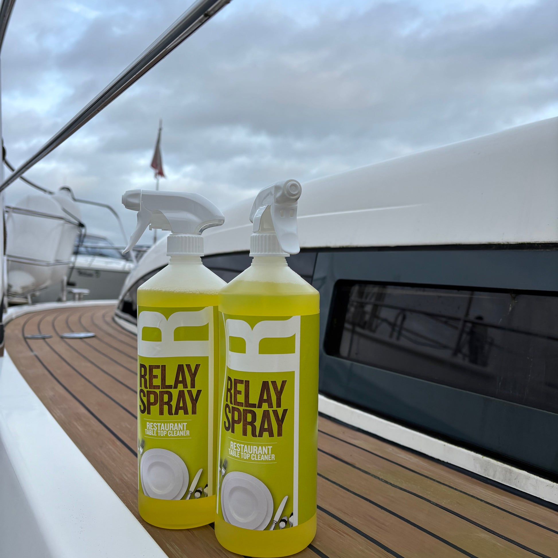 Two bottles of Delay Spray on a boat deck with water and sky in the background.