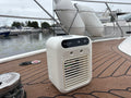 White portable air conditioner on a boat deck with water and boats in the background